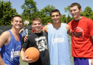 A close-up of fresh beets with reddish-purple roots and vibrant stems, some with green leaves still attached, piled together.