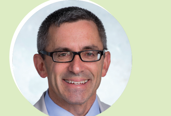 A middle-aged man with short dark hair, glasses, and a light blue collared shirt smiles at the camera against a light background with a pale green border.