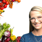 A woman with long blonde hair and glasses smiles in front of a white background, with various fresh vegetables and fruits, like tomatoes, carrots, and melons, arranged along the left side.
