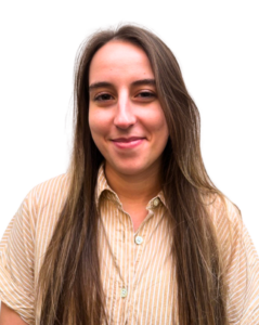 A woman with long brown hair, wearing a beige and white striped shirt, smiles slightly while facing the camera against a plain white background.