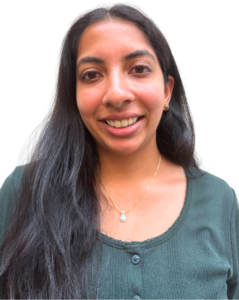 A woman with long dark hair, wearing a green buttoned shirt, a necklace, and earrings, smiles at the camera against a plain white background.